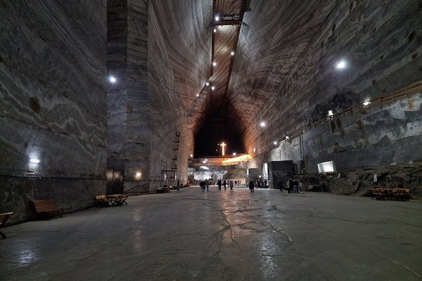 Un vaste espace souterrain, faiblement éclairé, avec de hauts plafonds et une zone centrale ouverte. 2