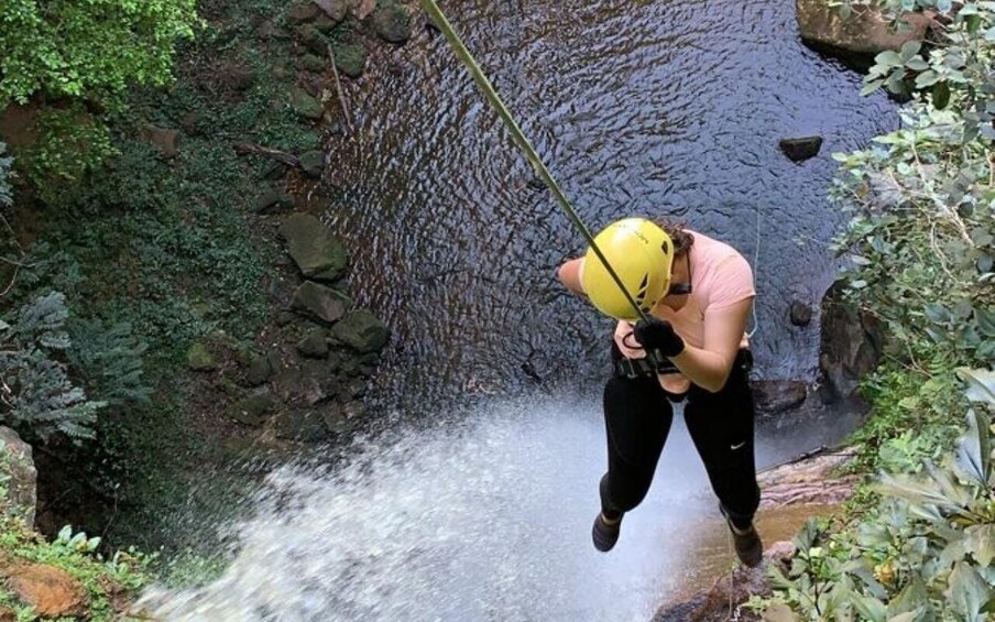 A person rappelling down a rocky waterfall. 5