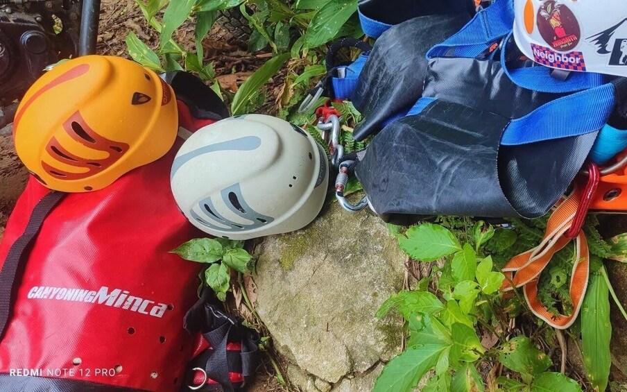 Two helmets, a red and a white one, and a black bag with a blue strap. 2