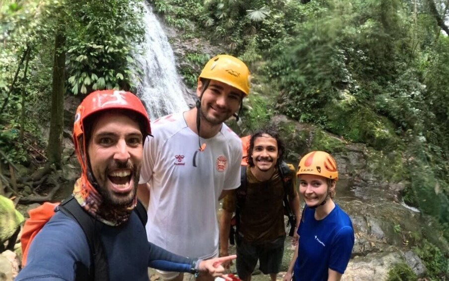 A group of people hiking in a forest with a waterfall in the background. 3