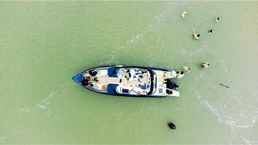 A boat docked in calm green water with people around it. 3