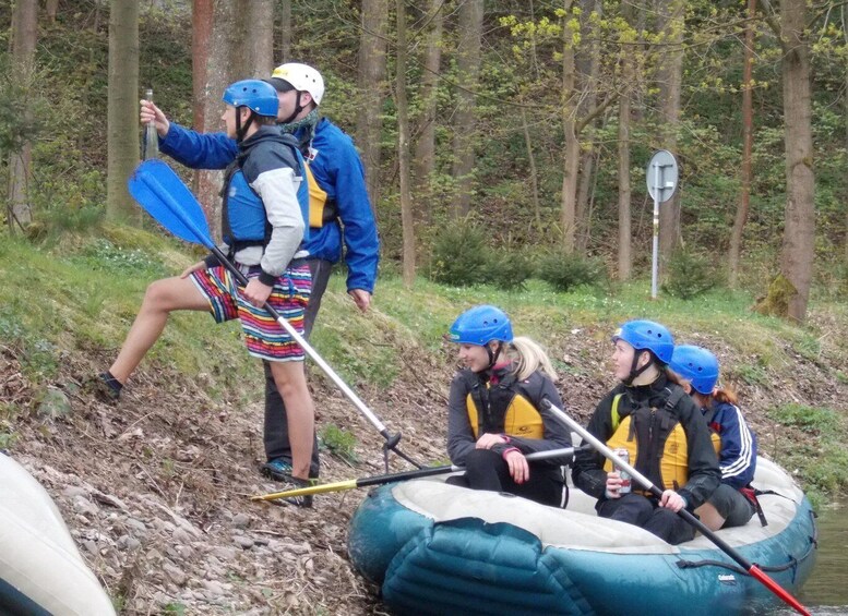 A group of people in a raft navigating a river, surrounded by trees. 3