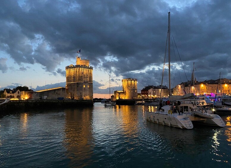 A historic waterfront with illuminated towers and a marina with boats. 2