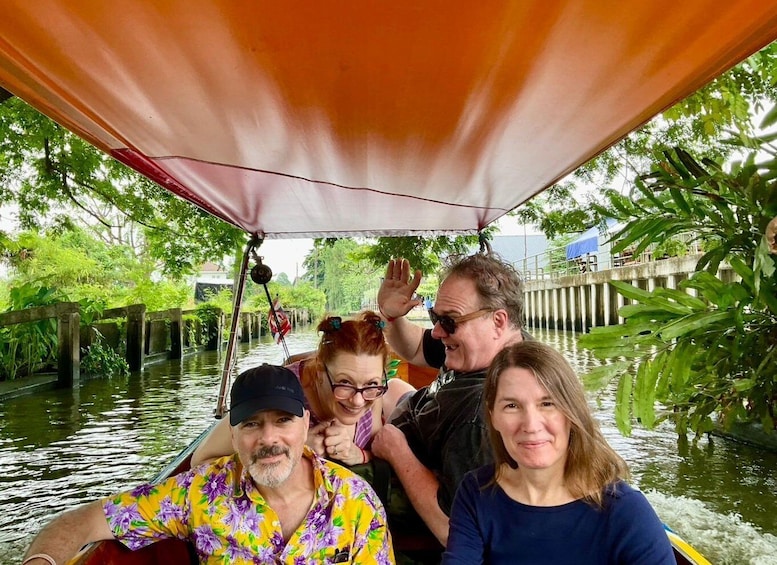 A group of people on a boat with a canopy, surrounded by water and greenery. 3
