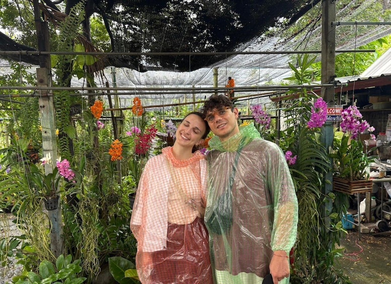 Two people standing in a greenhouse with various plants and flowers. 2