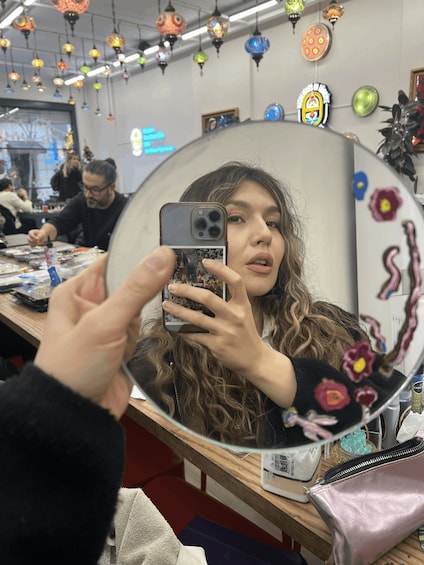 A person taking a selfie in a room with colorful hanging decorations and a mirror reflecting the scene. 4