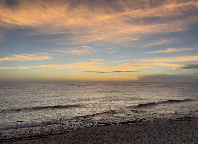 A beach with waves and a sunset sky. 5