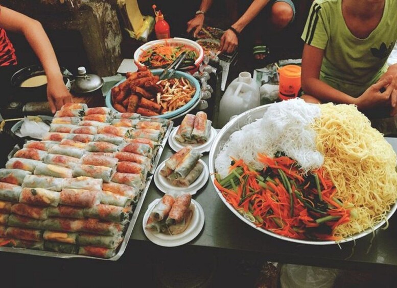 A table with various Vietnamese dishes, including spring rolls, noodles, and a salad. 2