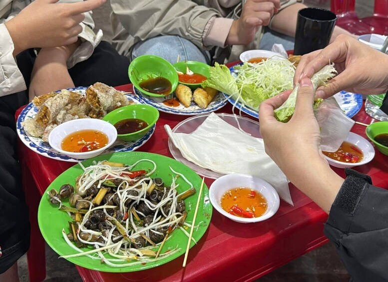 A table with various dishes, including a plate of greens, a bowl of soup, and a plate of fried items. 4
