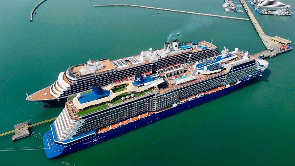 A large cruise ship docked at a port with multiple decks and a swimming pool. 2