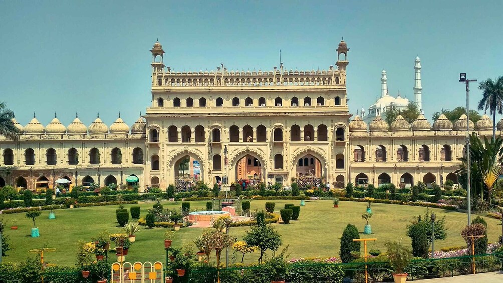 A large, ornate building with multiple domes and arches, surrounded by a well-maintained garden with various plants and a fountain. 2