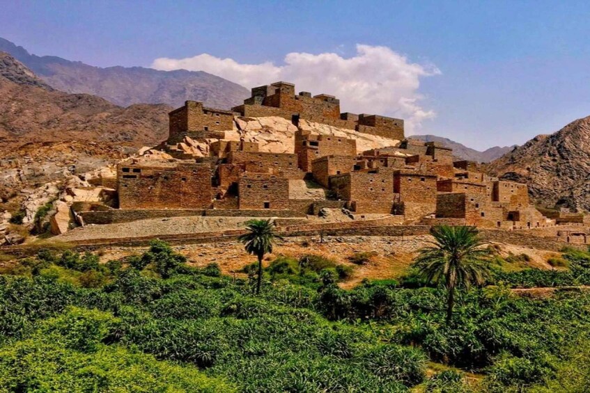 A historical fortress with multiple levels and towers, surrounded by rugged mountains and sparse vegetation. 3