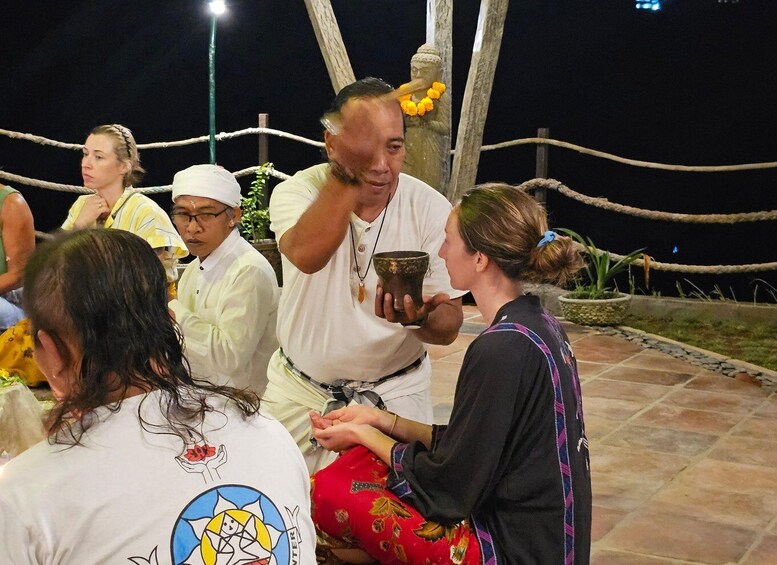 A group of people outdoors at night, gathered around a person holding a bowl. 3