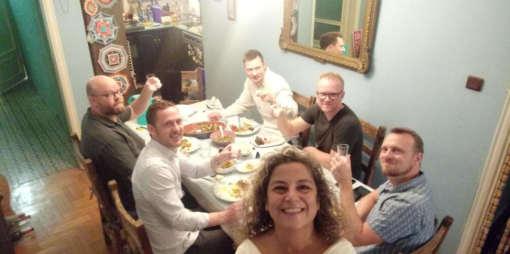 A group of people dining at a table with various dishes and glasses. 1