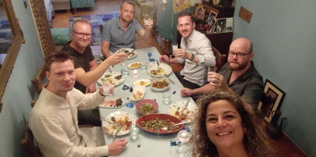 A group of people around a table with various dishes, glasses, and a bowl of salad. 5
