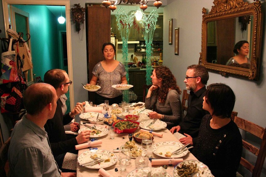 A group of people seated around a table with plates of food, engaged in a meal. 3