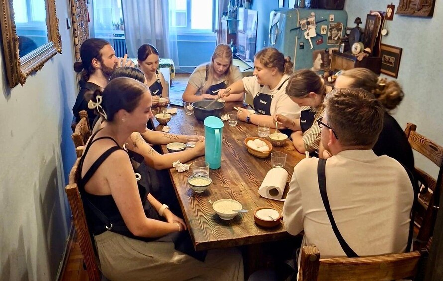 A group of people sitting around a wooden table in a room with framed pictures on the wall. 3
