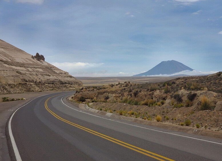 A winding road in a desert landscape with a mountain in the distance. 2