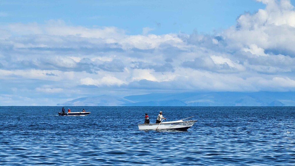 Two boats on calm blue waters with a cloudy sky and distant mountains. 3