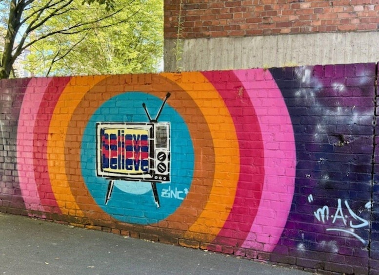 A colorful mural with a television set and the word 'believe' on a wall. 5