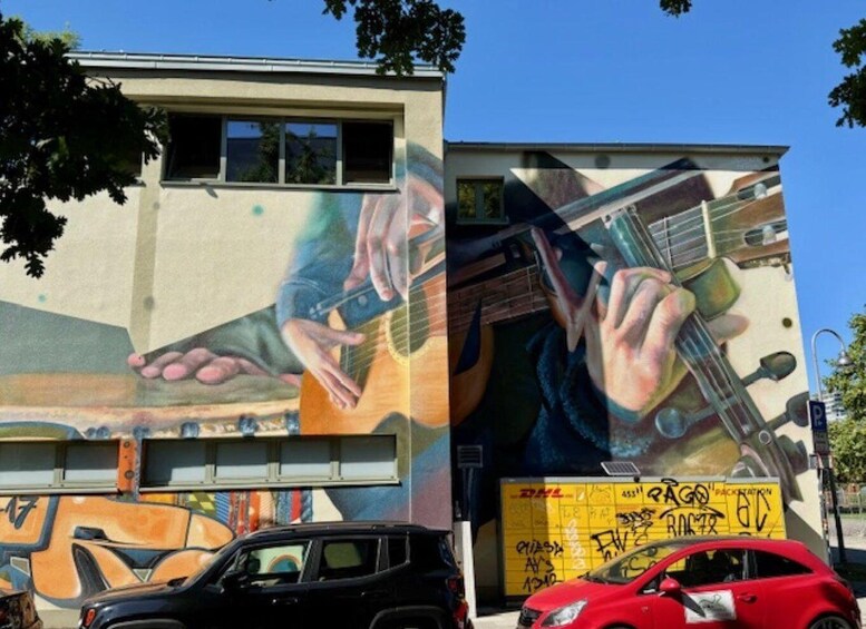 A building with a mural of hands playing a guitar and a DHL delivery box. 1