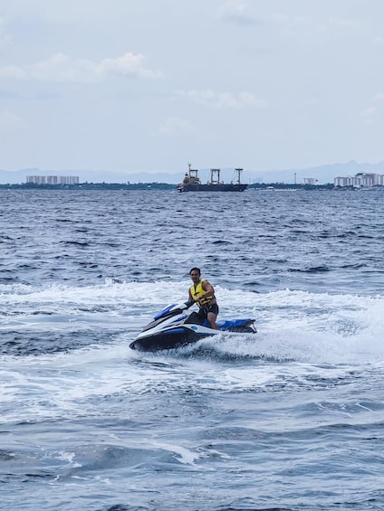 A person jet skiing on a body of water with a cargo ship in the background. 1