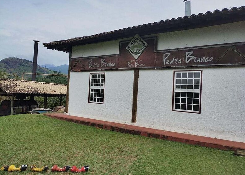 A white building with 'Pedro Branca' signage, surrounded by green grass and hills. 4