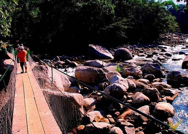 A wooden bridge over a rocky river with people walking on it. 3
