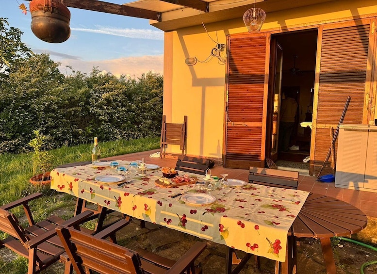 An outdoor dining area with a table set for two, surrounded by wooden chairs, a hanging pot, and a wooden door. 4