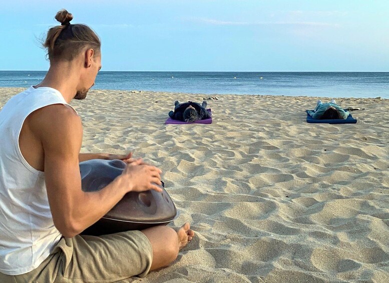 A person meditating on a sandy beach with the ocean in the background. 2