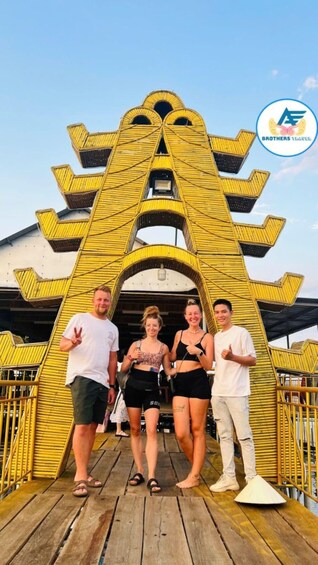 A group of people standing in front of a yellow, arrow-shaped structure with a logo in the corner. 3