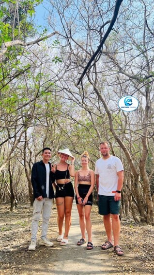 A group of people standing on a dirt path surrounded by trees. 5