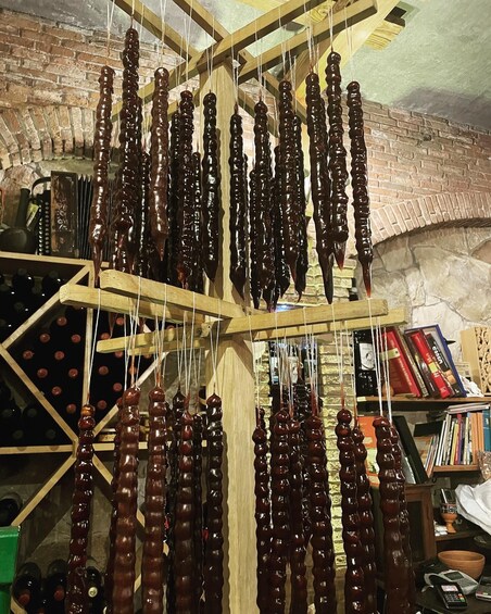 A wooden rack with multiple skewers of dark-colored food items hanging vertically. 3