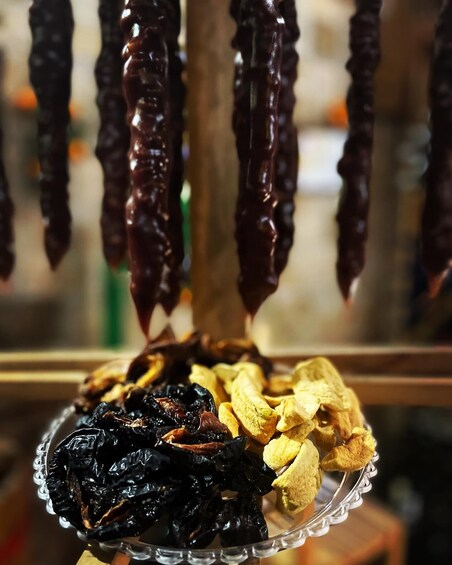 Dried red chilies and yellowish dried herbs hanging from a rack. 4
