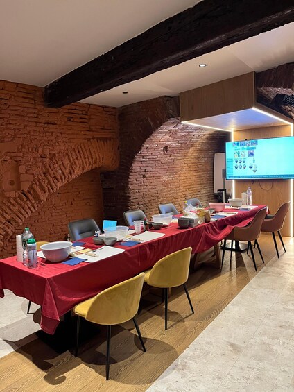 A conference room with a long table, chairs, a projector screen, and a brick wall. 3