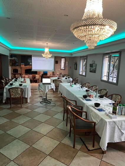 A banquet hall with tables set for a meal, a projector screen, and a large chandelier. 4