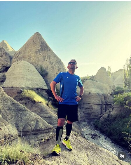 A person standing on a rocky terrain with large boulders and sparse vegetation. 3