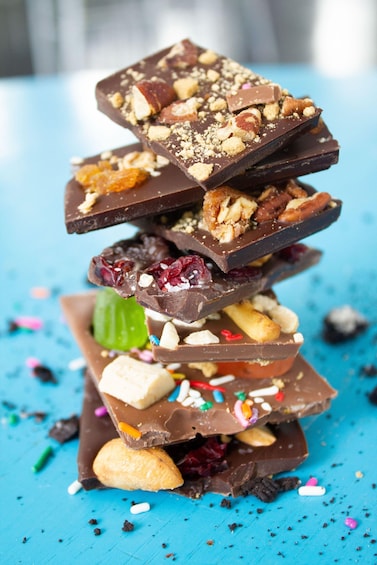 A stack of assorted chocolate bars with nuts and sprinkles. 1