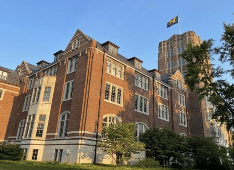 A large brick building with multiple windows and a flag on top. 5