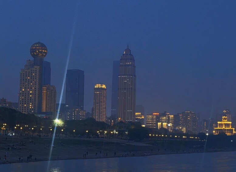 A city skyline at dusk with illuminated buildings and a beach in the foreground. 3