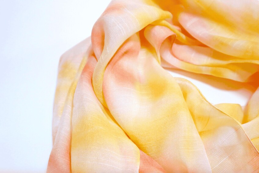 A close-up of a yellow and peach fabric with a smooth texture. 2