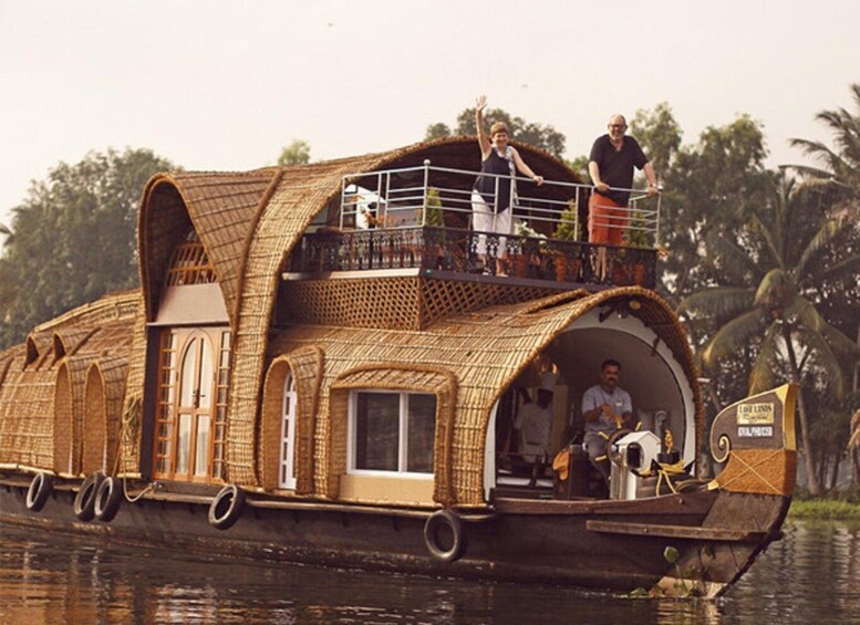 A houseboat with a thatched roof, a balcony, and a person on the deck. 1