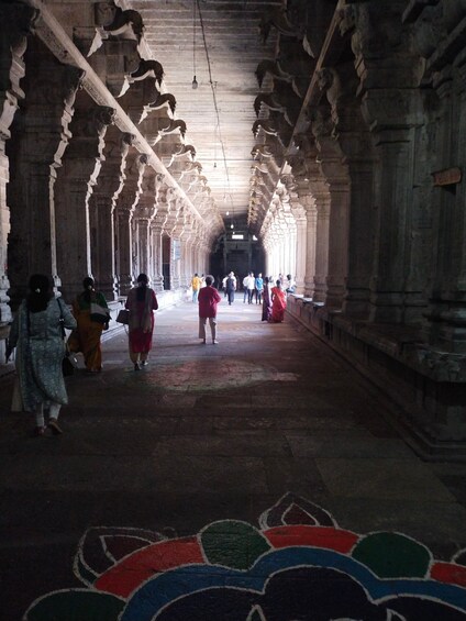 A corridor with ornate stone columns and a patterned floor. 3