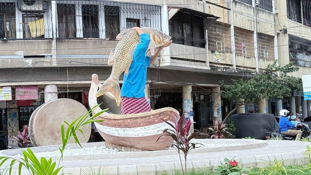 A large fish sculpture on a boat in an urban setting. 2