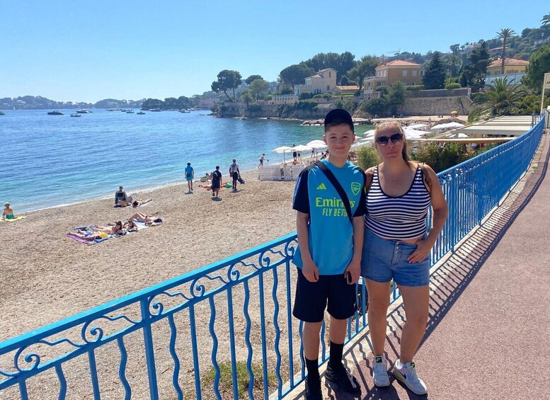 A coastal promenade with a beach, people sunbathing, and a blue railing. 2