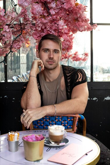 A person sitting at a table with a cup of coffee, a notebook, and a pen. 3