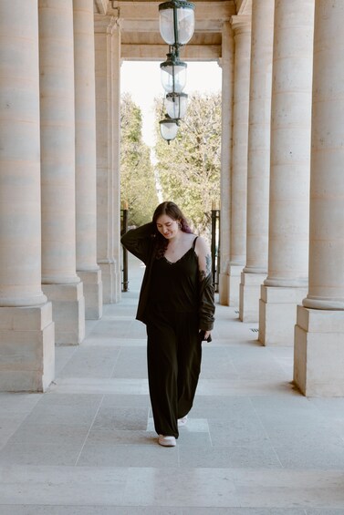 A person walking through a corridor with columns and a street lamp. 5