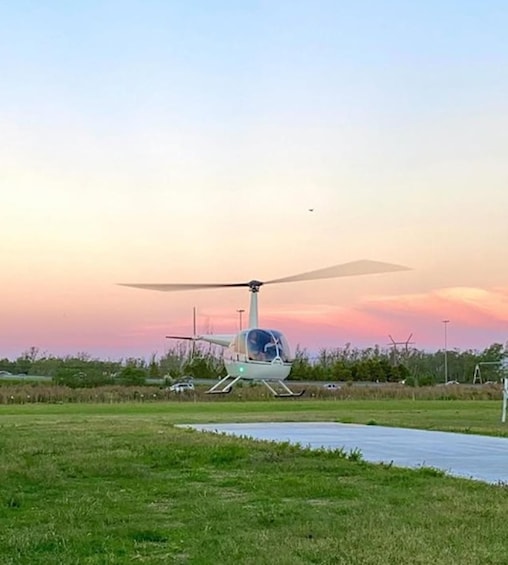 Helikopteri laskeutuu laskualustalle, taustalla auringonlasku. 4
