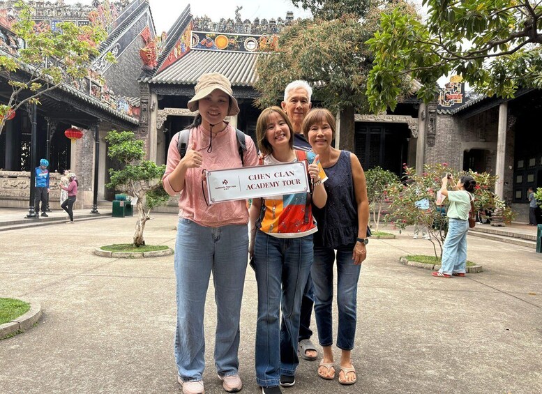 A group of people posing in front of a traditional building with intricate designs and a sign reading 'CHEN CLAN ACADEMY TOUR.' 4