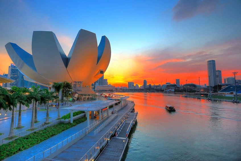 A waterfront promenade with a modern sculpture, palm trees, and a sunset. 5